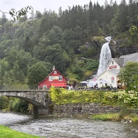 A waterfall behind the red houses by the fjord