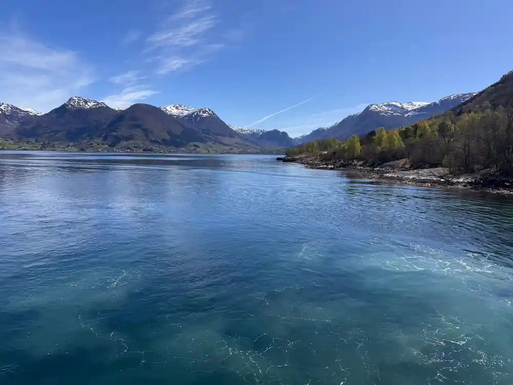a broad blue fjord between long ridges under a clear sky