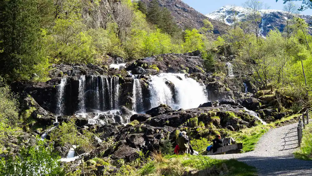 a broad waterfall dropping in stages down dark rock into green