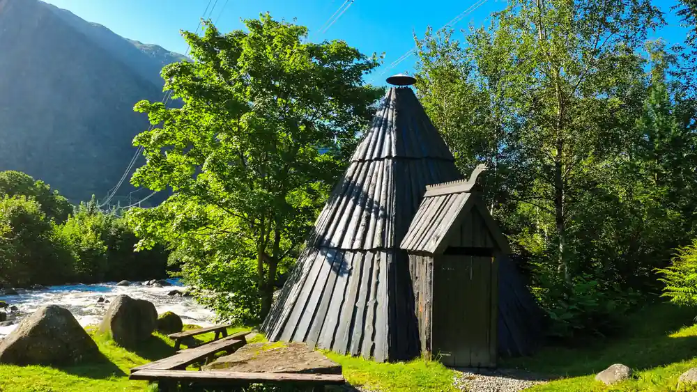 a conical timber hut in the manor grounds under summer trees