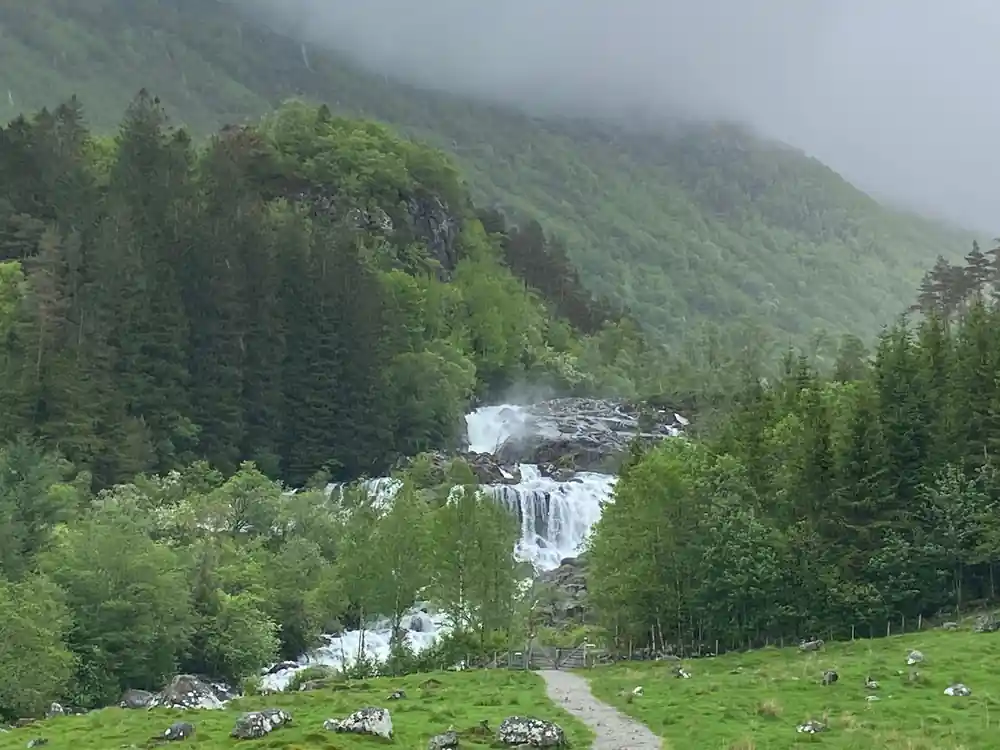 a long cascade coming down open hillside in soft rain