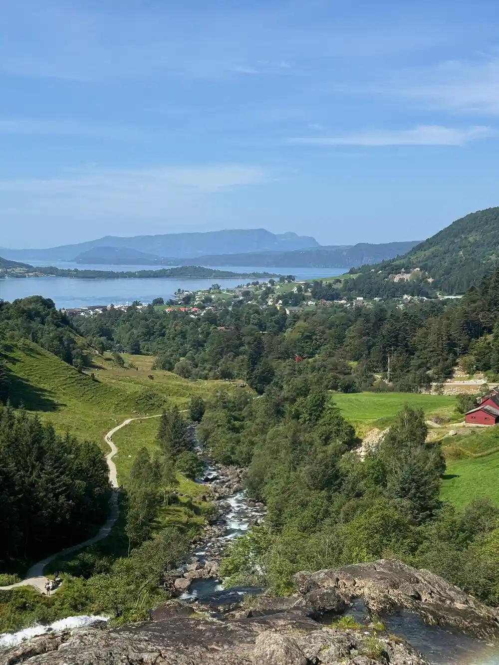 looking down a green valley to the fjord with a farm below