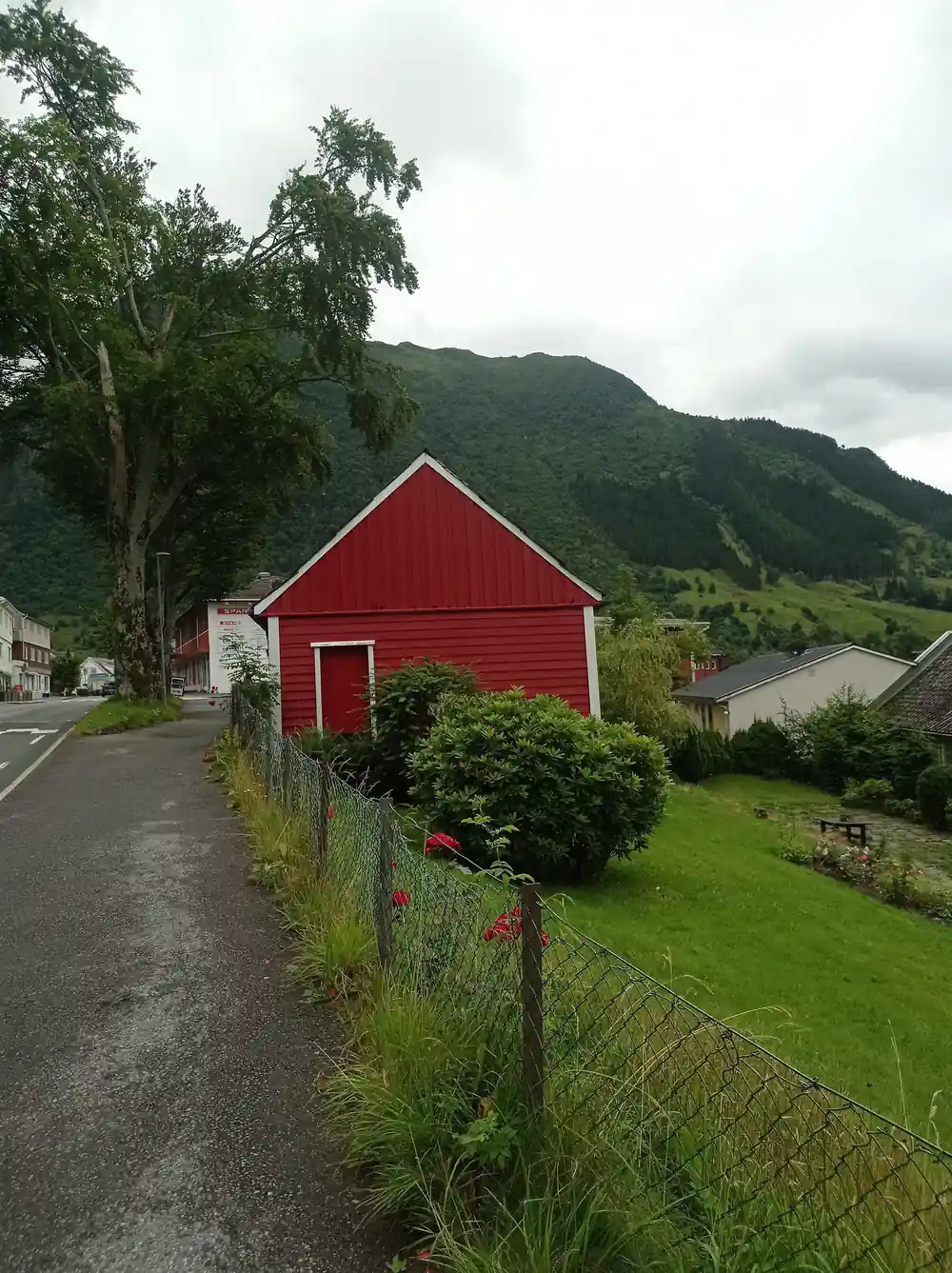 a red barn beside the village lane with the mountain behind