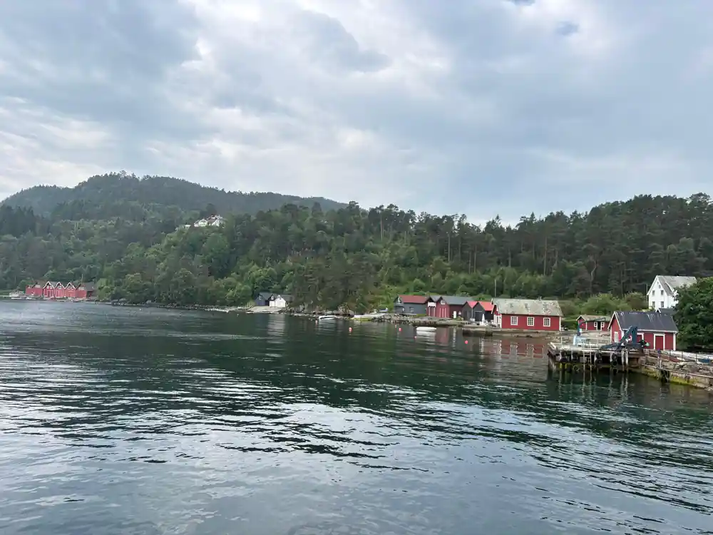 red boathouses along a quiet shore reflected in the water