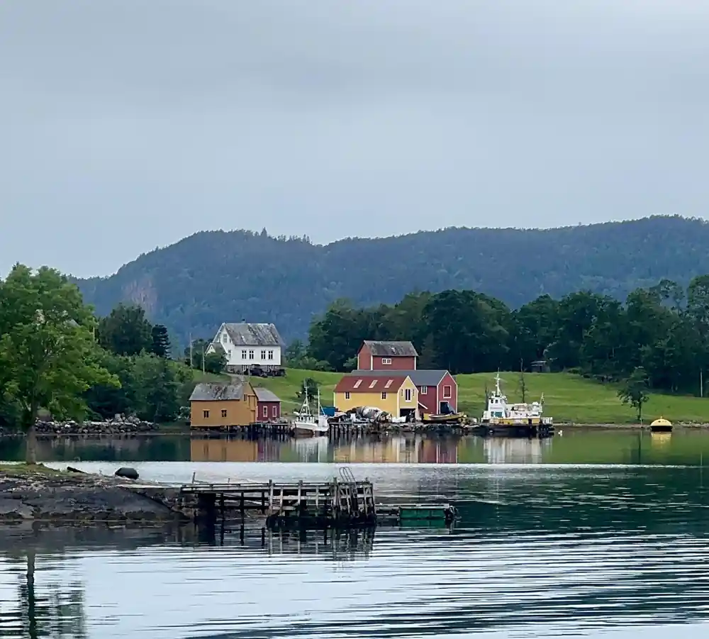 red and white boathouses on a wooded shore with a small pier