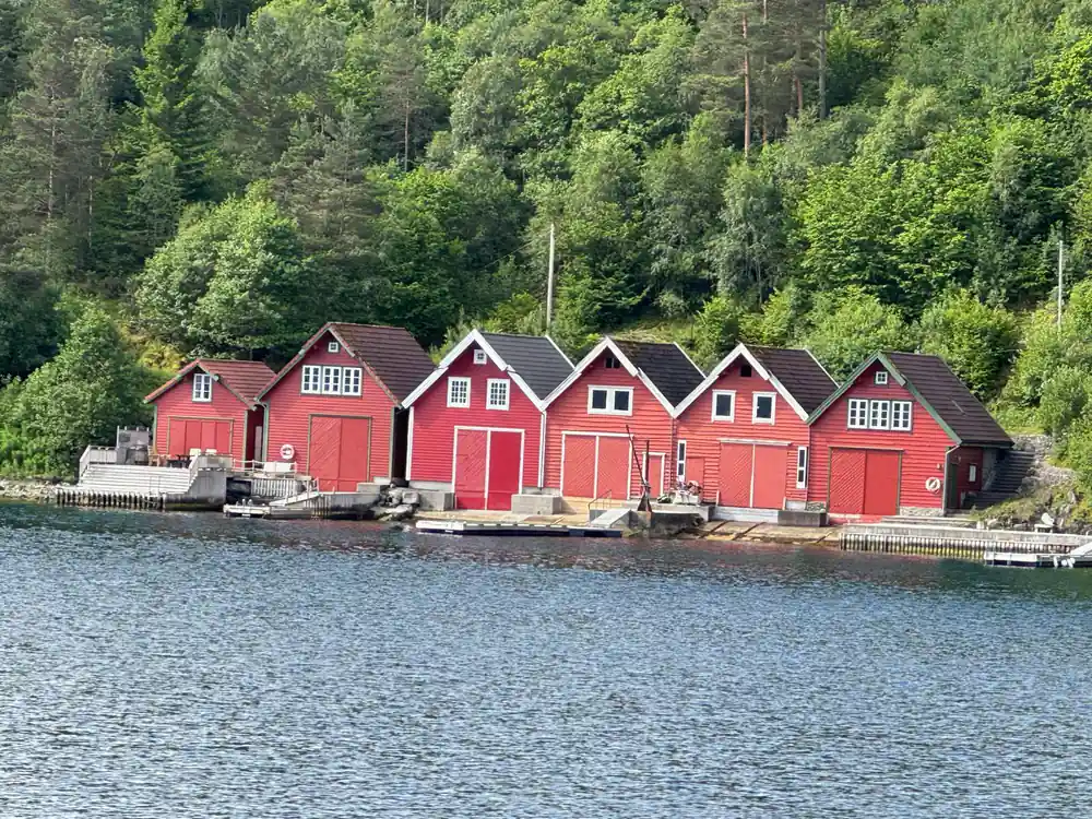 a row of red boathouses along the fjord shore