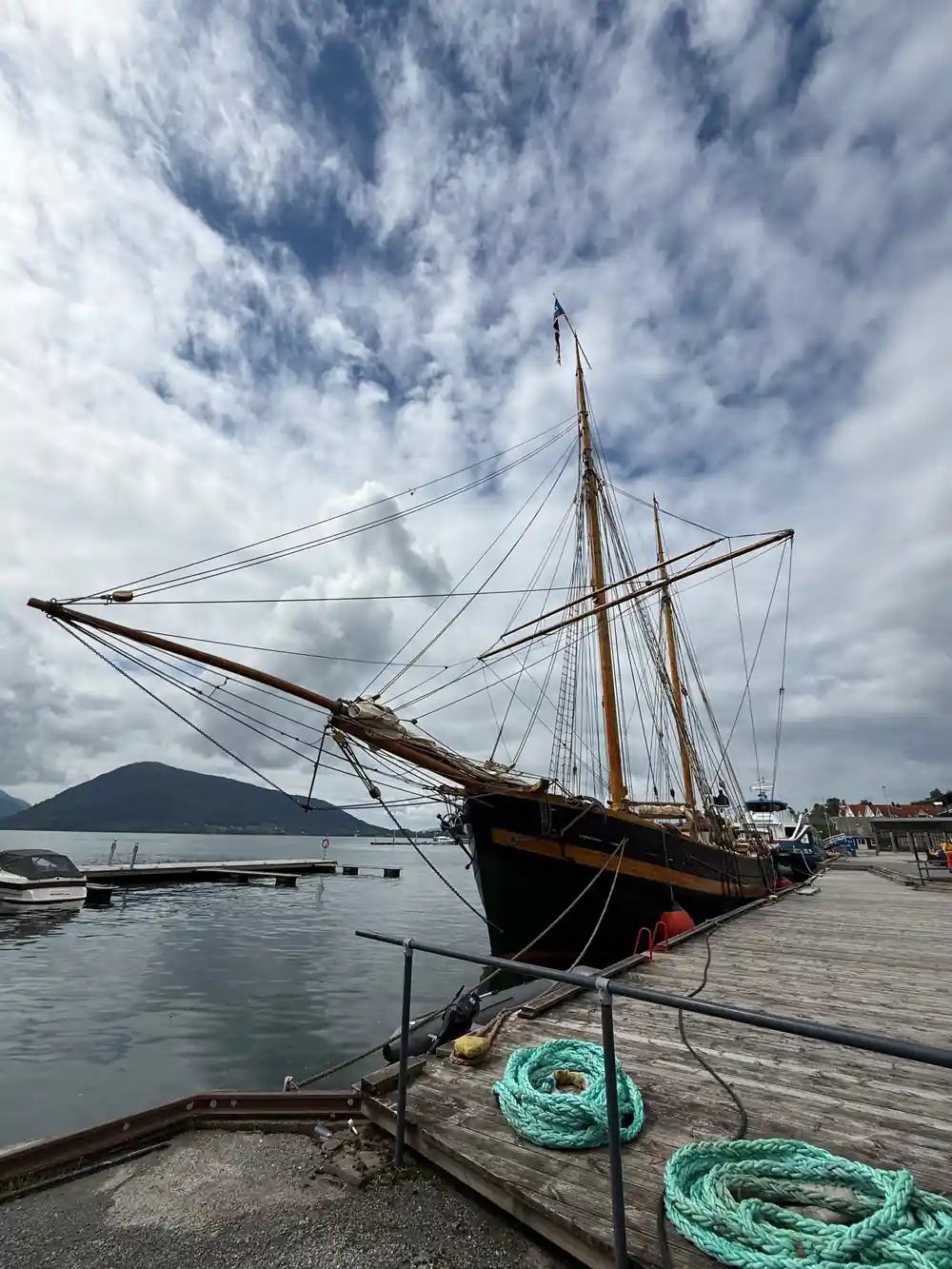 a wooden sailing vessel moored at a fjord pier
